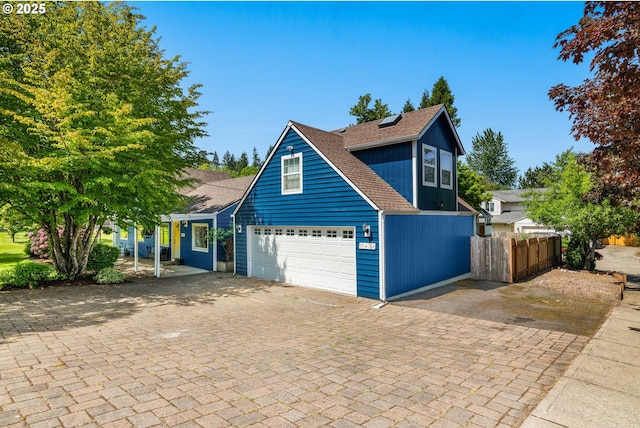 traditional home featuring fence, decorative driveway, and a shingled roof