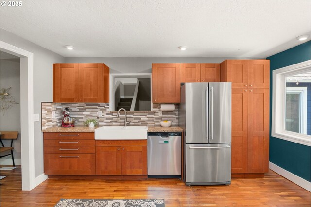 kitchen featuring stainless steel appliances, a sink, light wood-type flooring, decorative backsplash, and recessed lighting