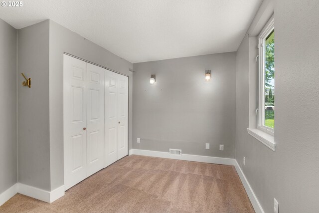 unfurnished bedroom featuring light carpet, multiple windows, and baseboards