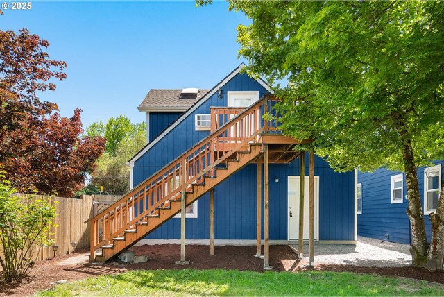 back of property with stairway, a deck, and fence