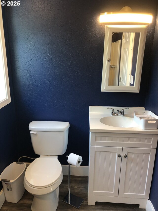 bathroom with wood finished floors, toilet, vanity, and baseboards
