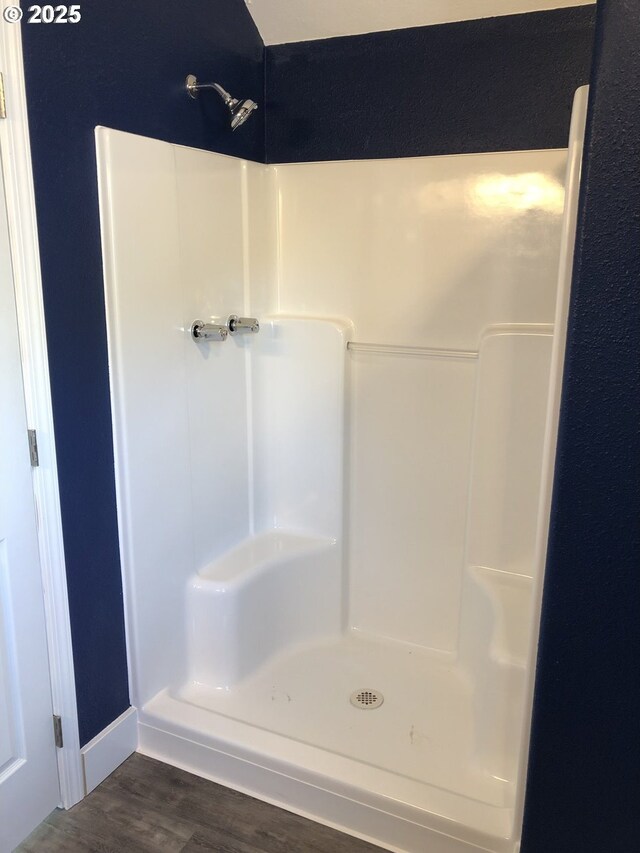 bathroom with a stall shower and wood finished floors