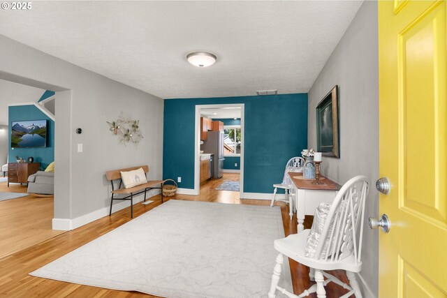 sitting room featuring wood finished floors, a textured ceiling, and baseboards