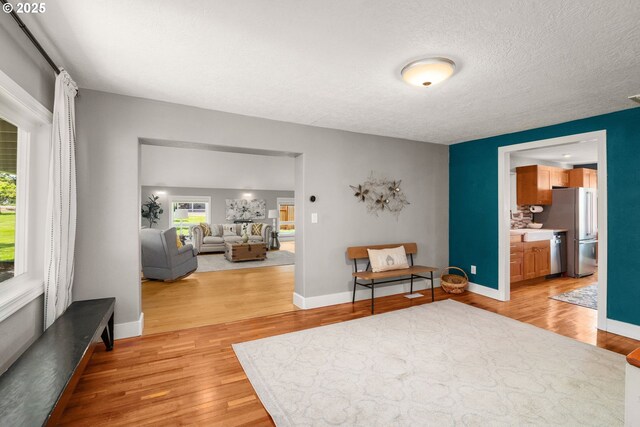 sitting room featuring light wood-style flooring, healthy amount of natural light, baseboards, and a textured ceiling