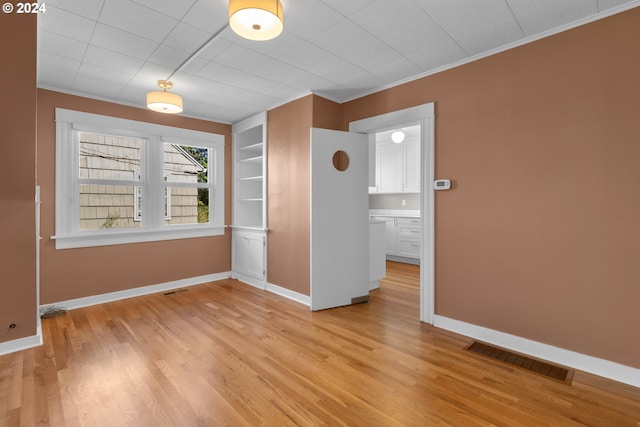 spare room with visible vents, baseboards, light wood-style flooring, and crown molding