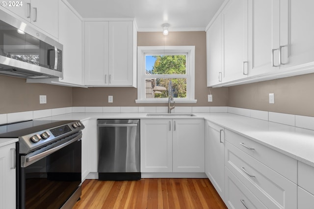 kitchen with white cabinetry, stainless steel appliances, light wood-type flooring, and a sink