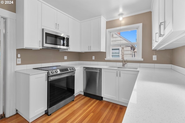 kitchen with a sink, stainless steel appliances, light wood-type flooring, and white cabinetry