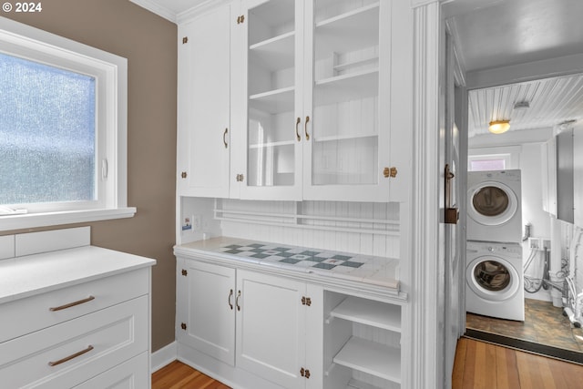 laundry room featuring laundry area, stacked washer and dryer, and light wood finished floors