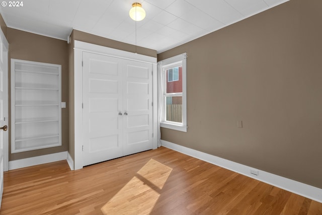 unfurnished bedroom with a closet, light wood-style flooring, and baseboards