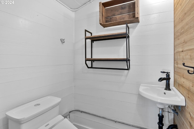 bathroom featuring toilet and wood walls