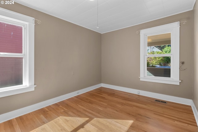 empty room featuring visible vents, baseboards, and light wood finished floors