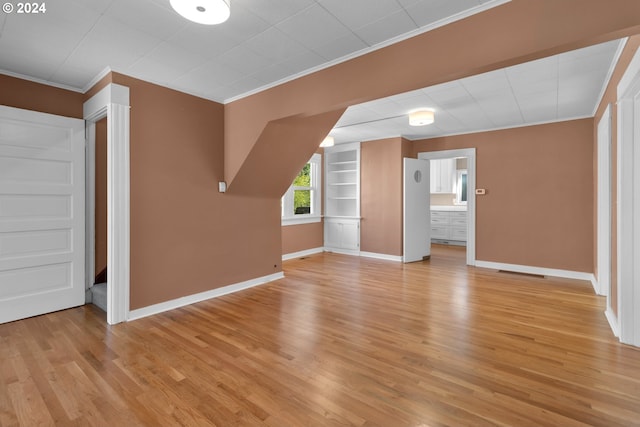 additional living space featuring built in shelves, baseboards, and light wood finished floors