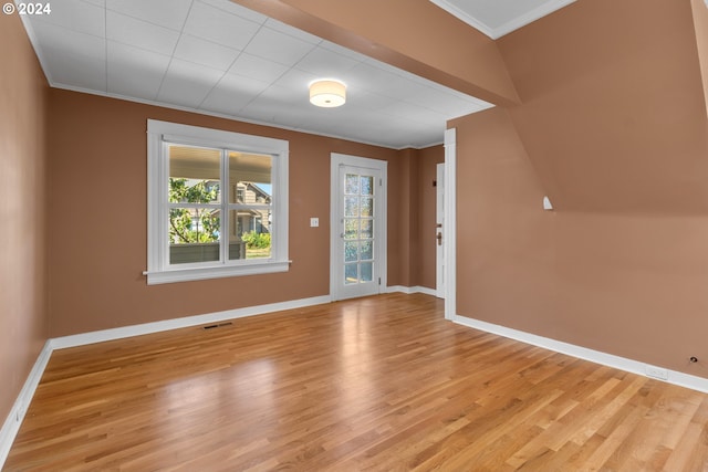 foyer featuring light wood finished floors, visible vents, baseboards, and ornamental molding