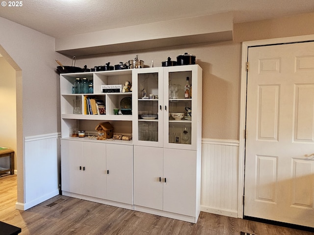 interior details with arched walkways, wood finished floors, and wainscoting