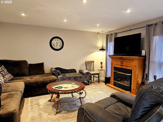 living room featuring a glass covered fireplace, recessed lighting, and wood finished floors