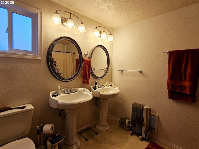 full bath featuring toilet, a textured ceiling, radiator heating unit, baseboards, and a textured wall