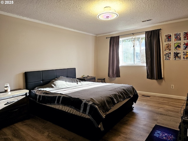 bedroom featuring visible vents, baseboards, a textured ceiling, and wood finished floors