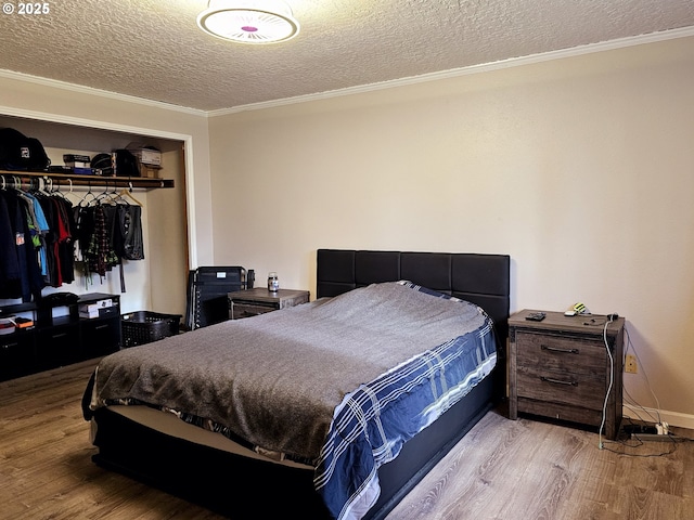 bedroom featuring a closet, a textured ceiling, wood finished floors, and crown molding