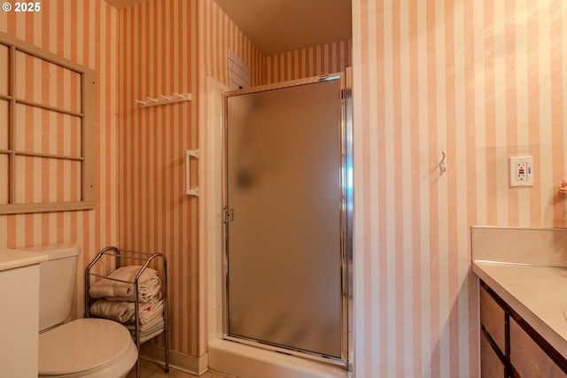 full bathroom with a stall shower, vanity, toilet, and wallpapered walls