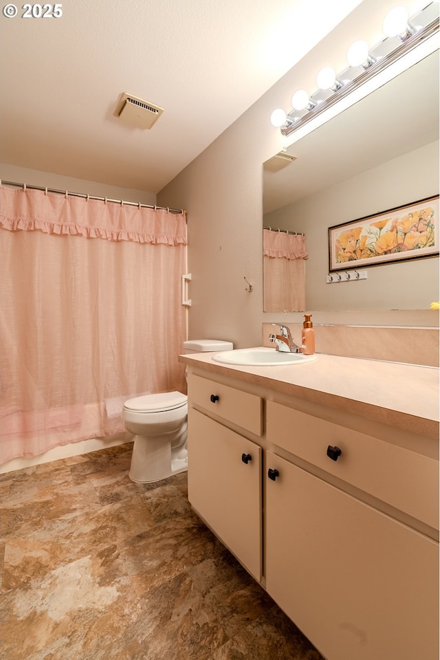 bathroom with visible vents, toilet, curtained shower, stone finish flooring, and vanity