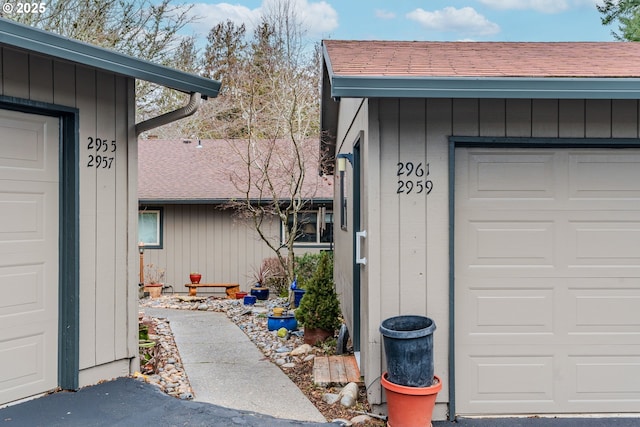 entrance to property featuring a garage and a shingled roof