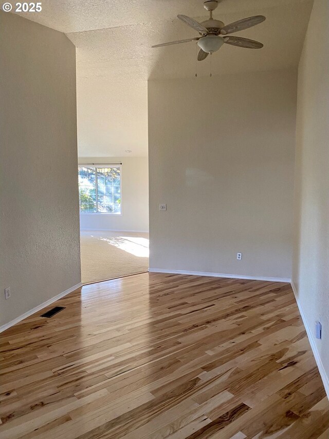 unfurnished room featuring baseboards, ceiling fan, visible vents, and wood finished floors