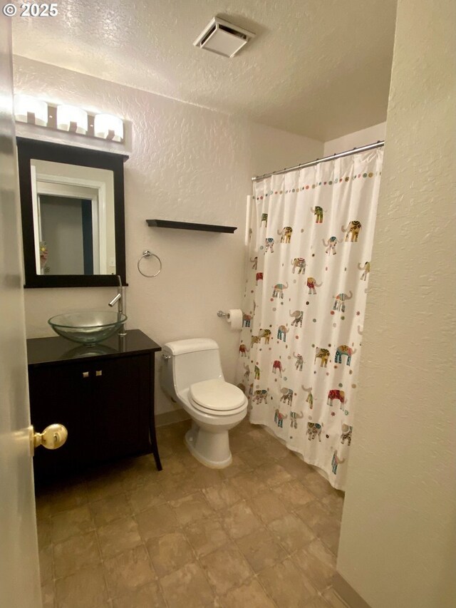 bathroom featuring a textured wall, toilet, a textured ceiling, a shower with curtain, and visible vents