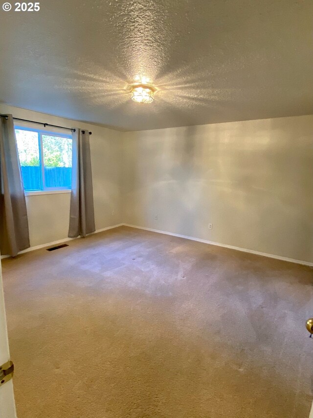 unfurnished room featuring carpet floors, a textured ceiling, visible vents, and baseboards
