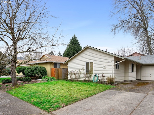 view of side of property featuring a garage, a lawn, driveway, and fence