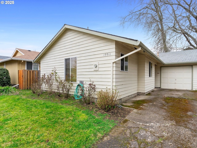 view of side of home featuring driveway, an attached garage, a yard, and fence