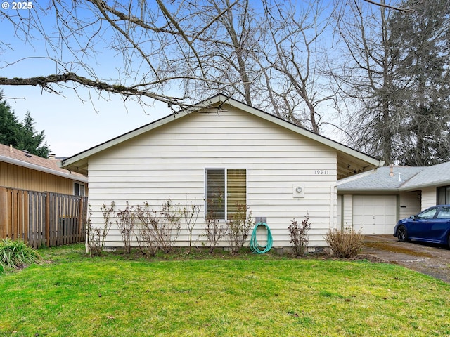 exterior space featuring a lawn, an attached garage, and fence