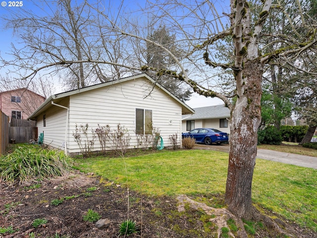 view of side of property featuring driveway, a yard, and fence