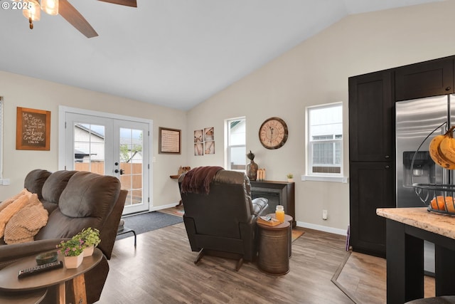 living room with lofted ceiling, a wealth of natural light, light wood-type flooring, and french doors