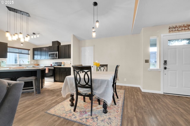 dining room featuring baseboards, lofted ceiling, and light wood-type flooring