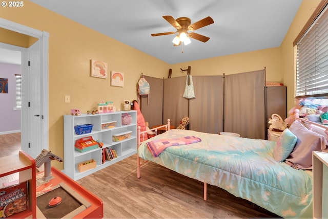 bedroom featuring a ceiling fan, wood finished floors, and multiple windows