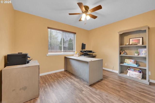 office featuring light wood finished floors, baseboards, and ceiling fan