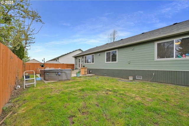 back of house featuring a lawn, a hot tub, a fenced backyard, and crawl space