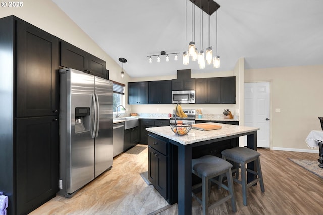 kitchen with a kitchen bar, a sink, decorative light fixtures, and stainless steel appliances