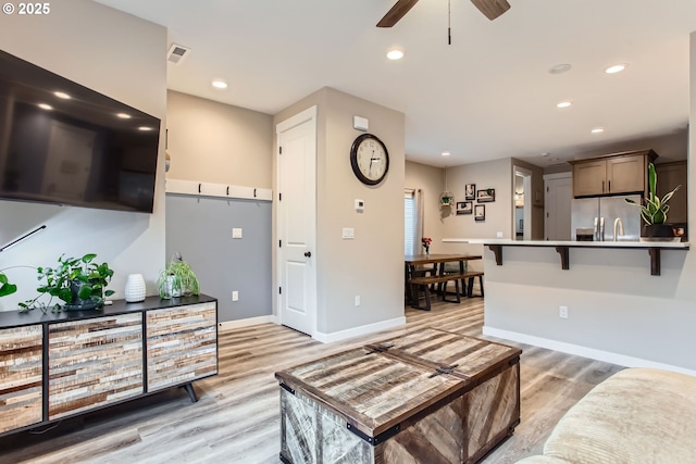 living area with light wood-style flooring, visible vents, and recessed lighting