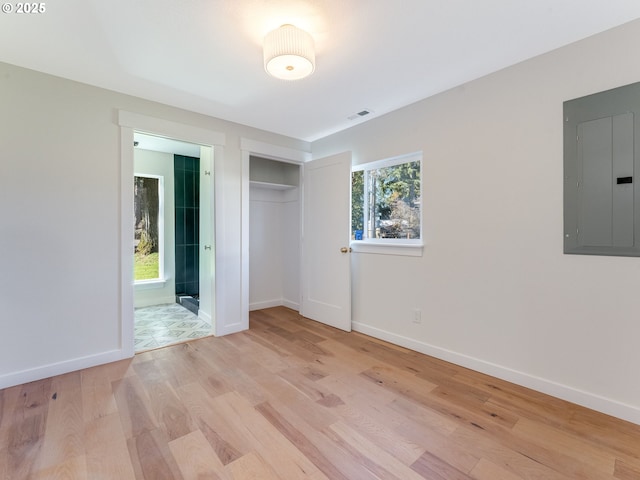 unfurnished bedroom with light wood finished floors, a closet, visible vents, electric panel, and baseboards