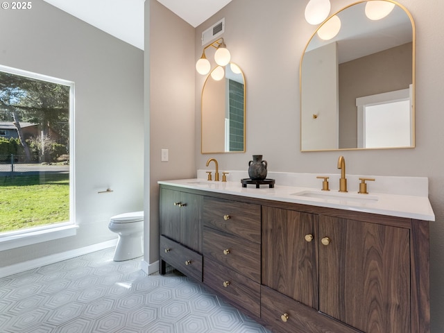 full bathroom featuring toilet, double vanity, a sink, and visible vents