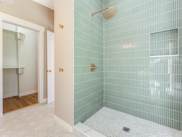 full bathroom featuring tiled shower and baseboards