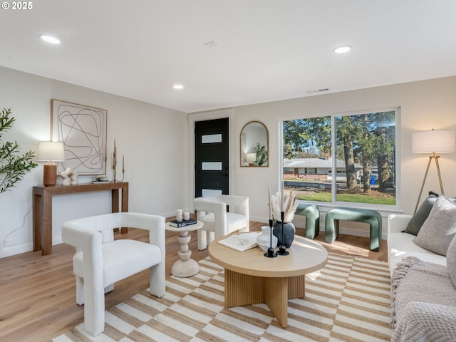 living room with baseboards, visible vents, light wood-style flooring, and recessed lighting