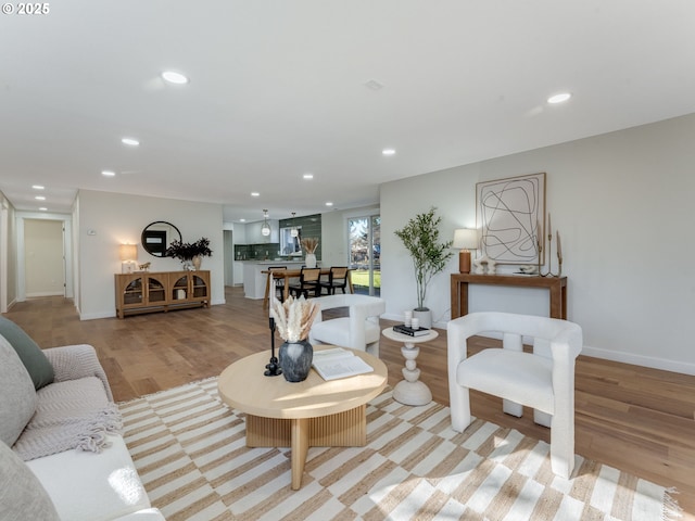 living area with baseboards, light wood-type flooring, and recessed lighting