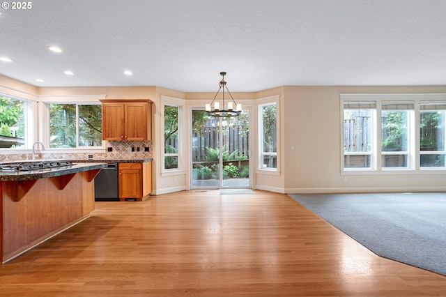 3578 NW Gerritz Ter, Portland, OR 97229 - kitchen featuring dishwasher, a chandelier, dark countertops, open floor plan, and light wood-style flooring