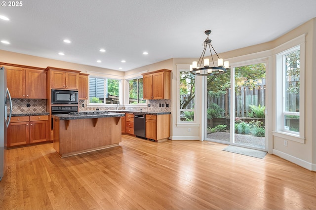 3578 NW Gerritz Ter, Portland, OR 97229 - kitchen with black appliances, a chandelier, backsplash, a breakfast bar, and recessed lighting