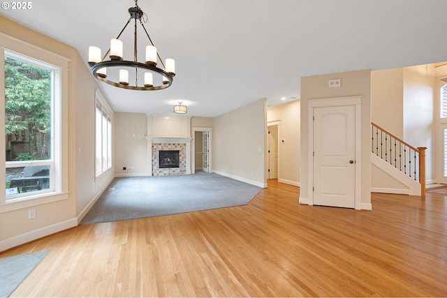 3578 NW Gerritz Ter, Portland, OR 97229 - unfurnished living room with light wood-style flooring, baseboards, a chandelier, a fireplace, and stairs