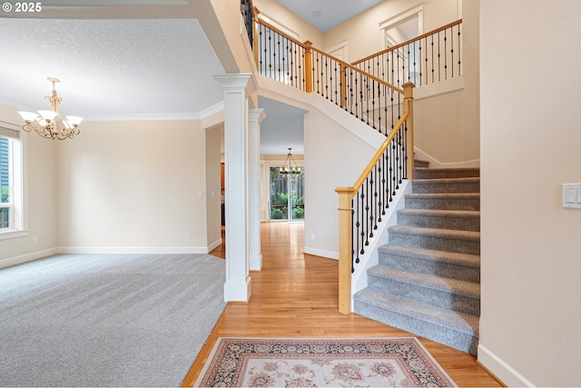 3578 NW Gerritz Ter, Portland, OR 97229 - staircase with a chandelier, wood finished floors, baseboards, decorative columns, and ornamental molding