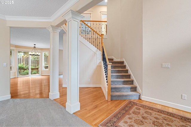3578 NW Gerritz Ter, Portland, OR 97229 - stairway with a chandelier, wood finished floors, ornate columns, baseboards, and ornamental molding
