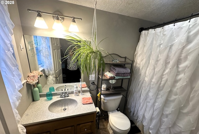 bathroom with vanity, toilet, and a textured ceiling